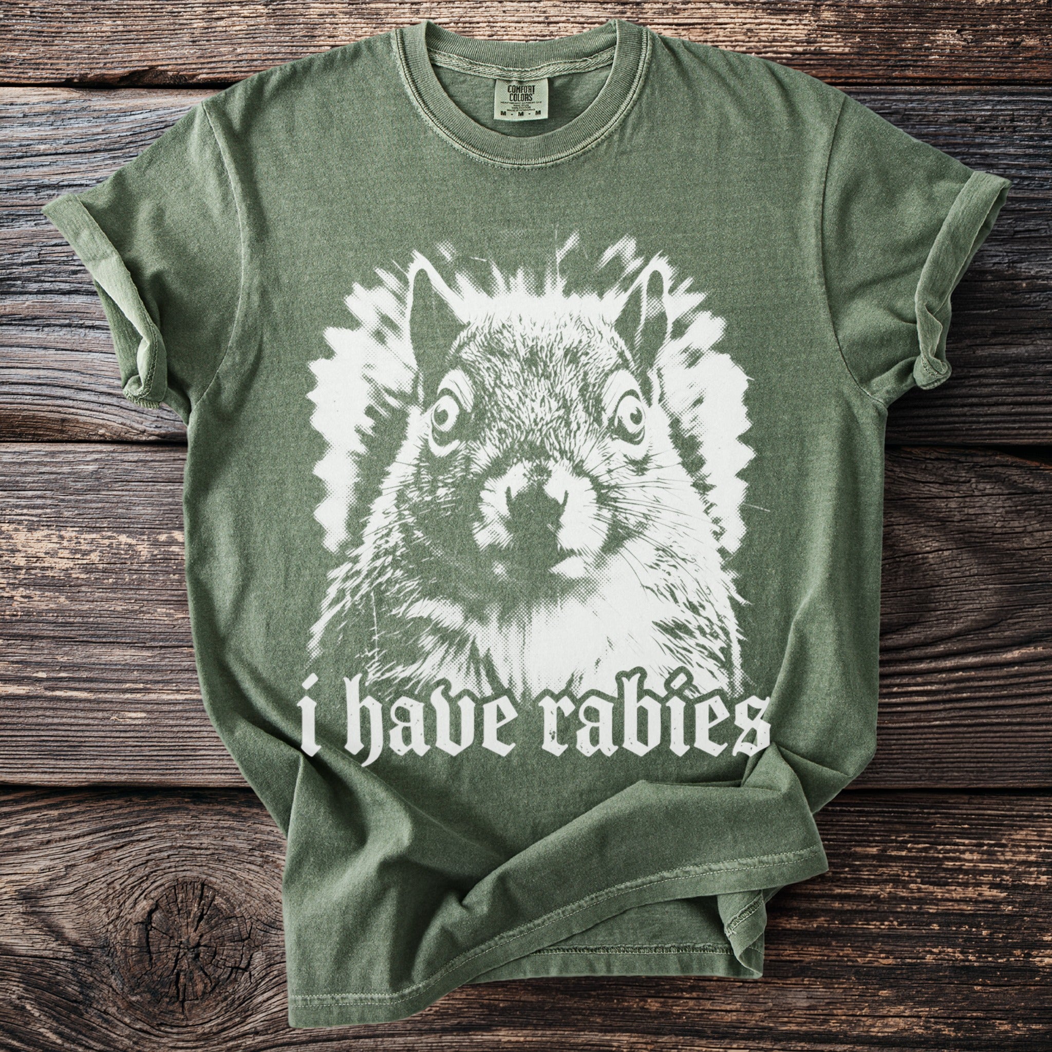 Green t-shirt with a white graphic of a squirrel and "i have rabies" text.