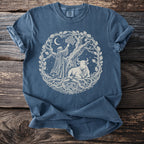 Blue t-shirt with cream circular print of a robed figure, bull, and tree.
