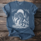 Blue t-shirt with a white graphic of a werewolf in a forest under a full moon.