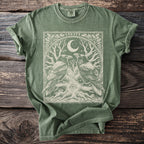 Green t-shirt with a linocut design of two ravens, a moon, and a tree with an eye.