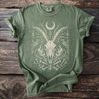 Green t-shirt with cream graphic of goat skull, moons, crows, and bones.