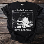 Black t-shirt with text "god forbid women have hobbies" and a vintage image.