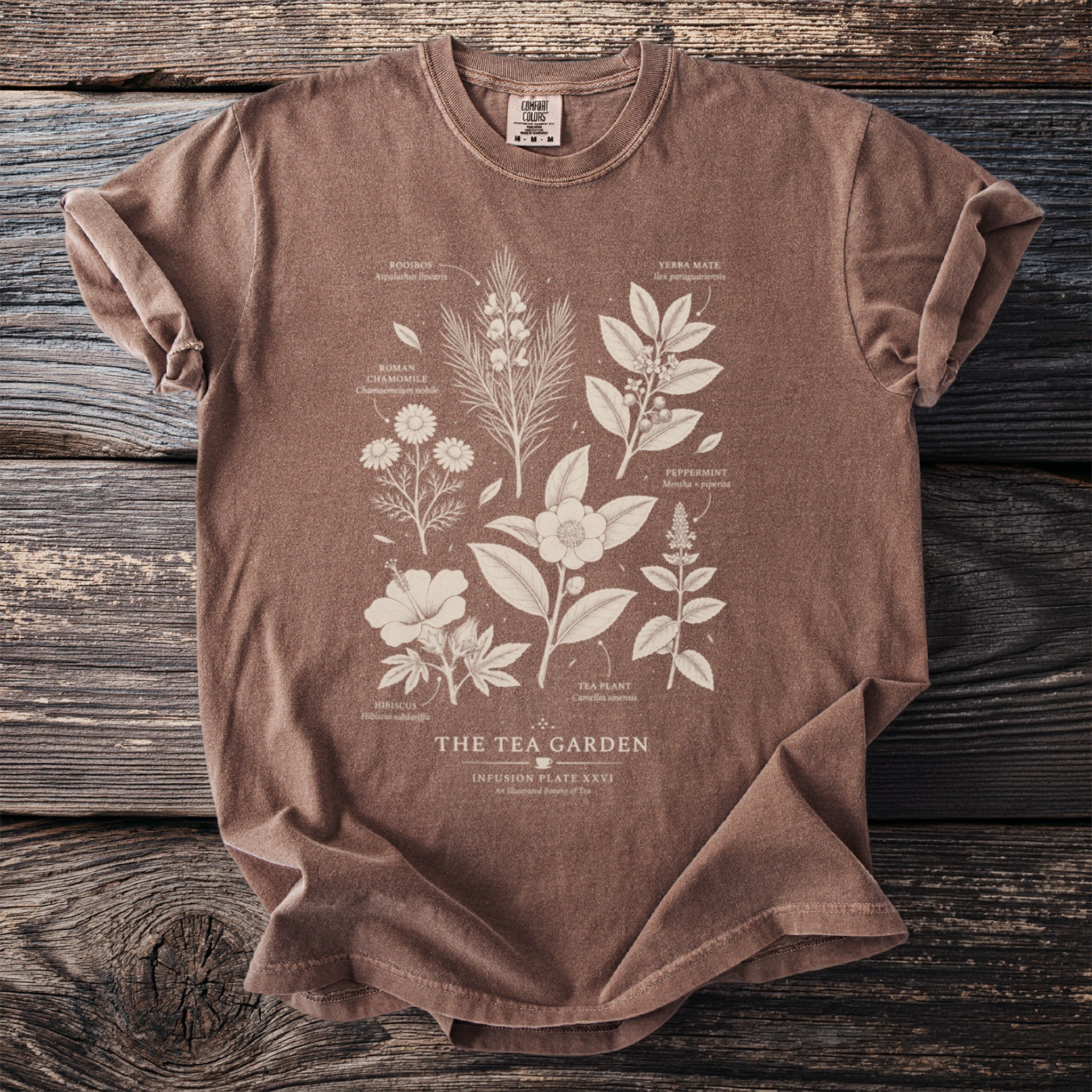 Brown shirt with botanical illustrations of tea garden plants and text.
