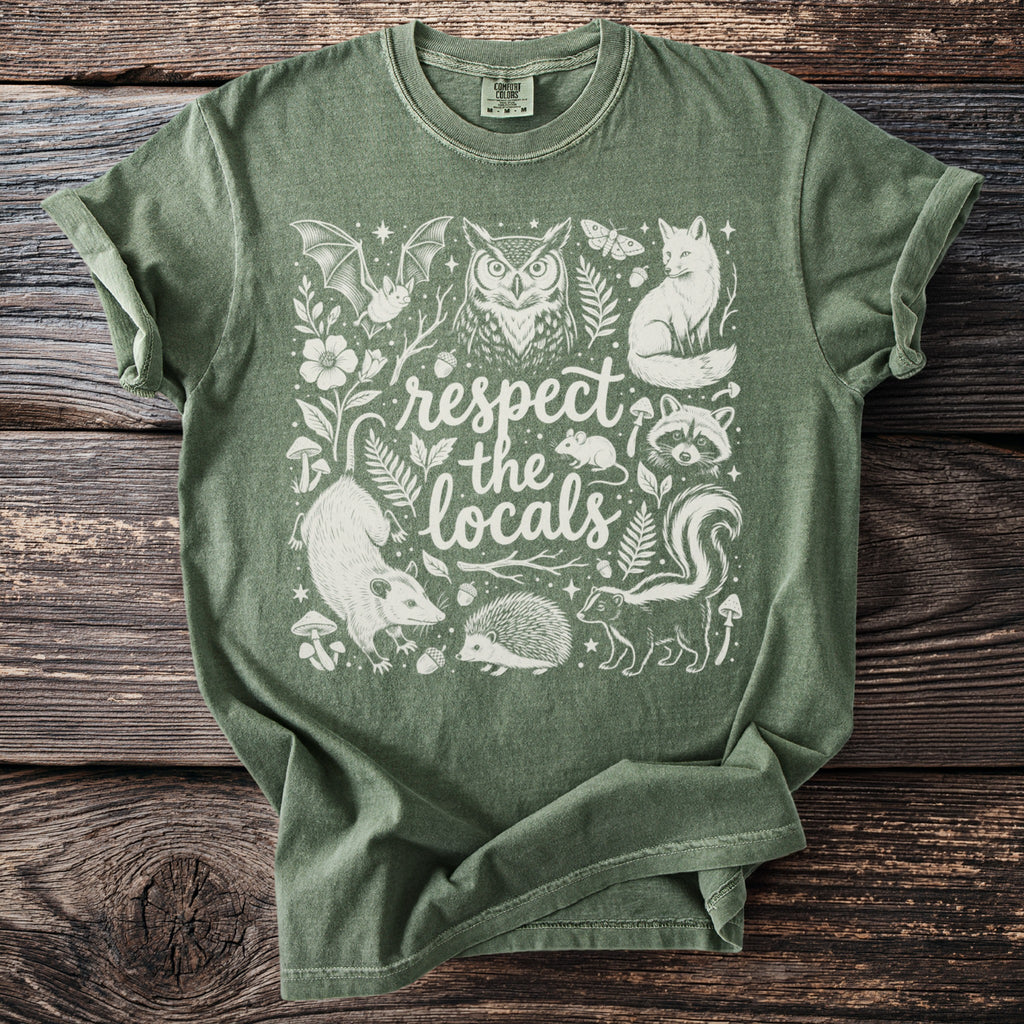 Green t-shirt with white illustration of forest animals and "respect the locals" text.
