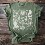 Green t-shirt with white illustration of forest animals and "respect the locals" text.