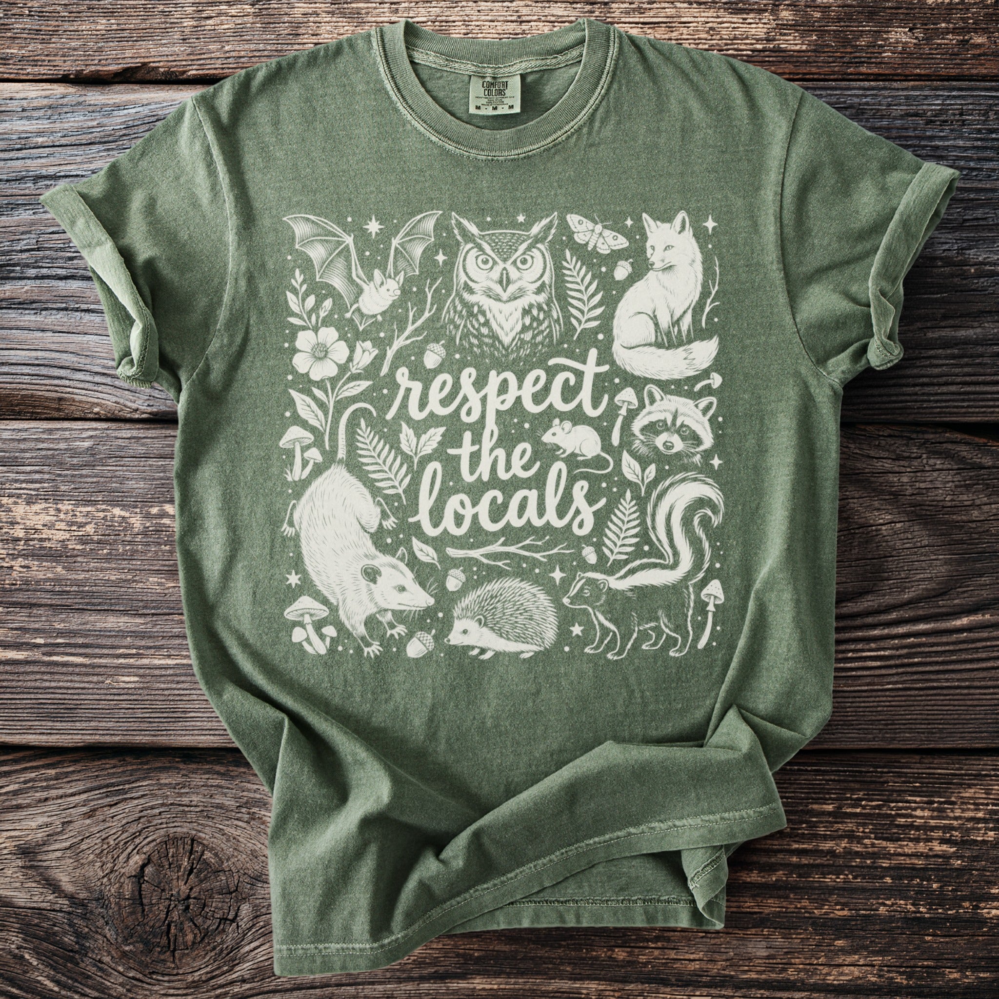 Green t-shirt with white illustration of forest animals and "respect the locals" text.