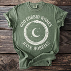Green t-shirt with white text and graphic of snake, moon, and stars.