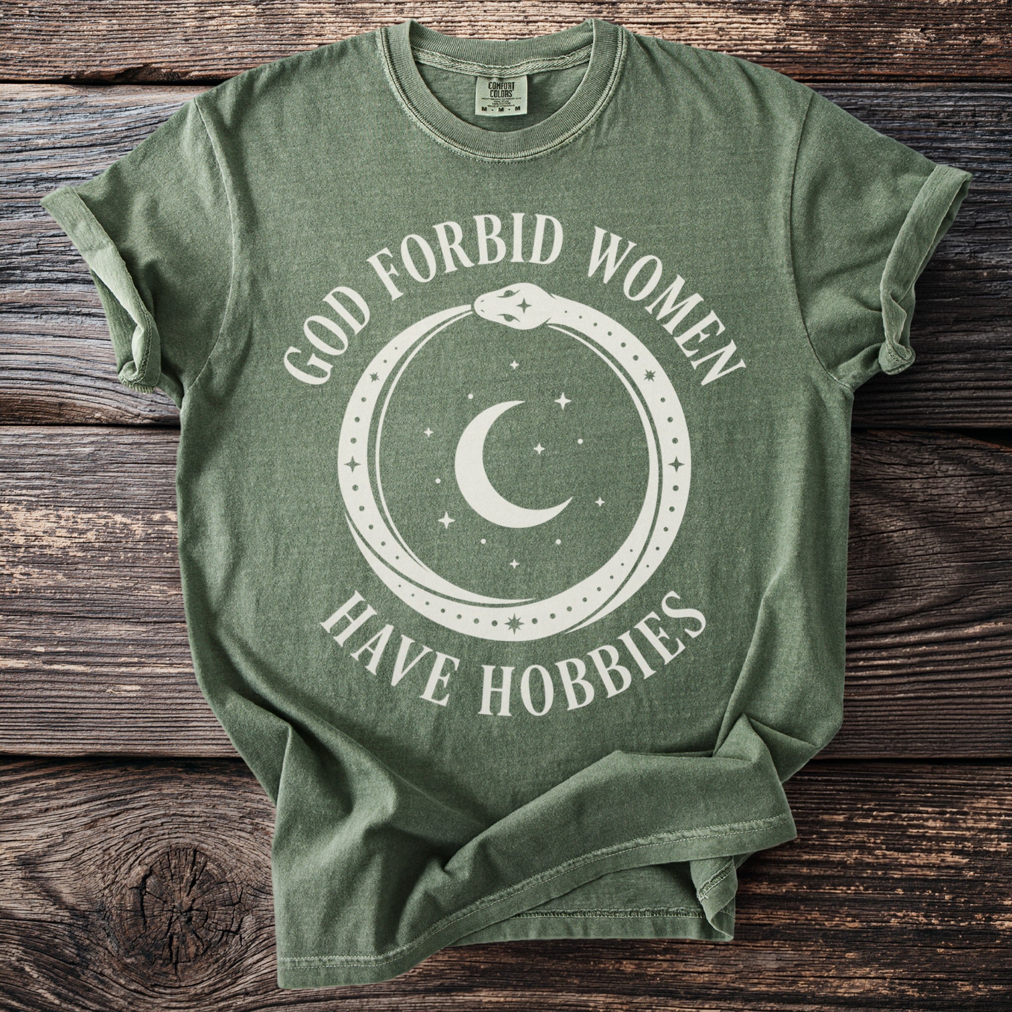 Green t-shirt with white text and graphic of snake, moon, and stars.