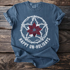 Blue T-shirt with white pentagram, barbed wire, and poinsettia, reads "Happy Un-Holidays".