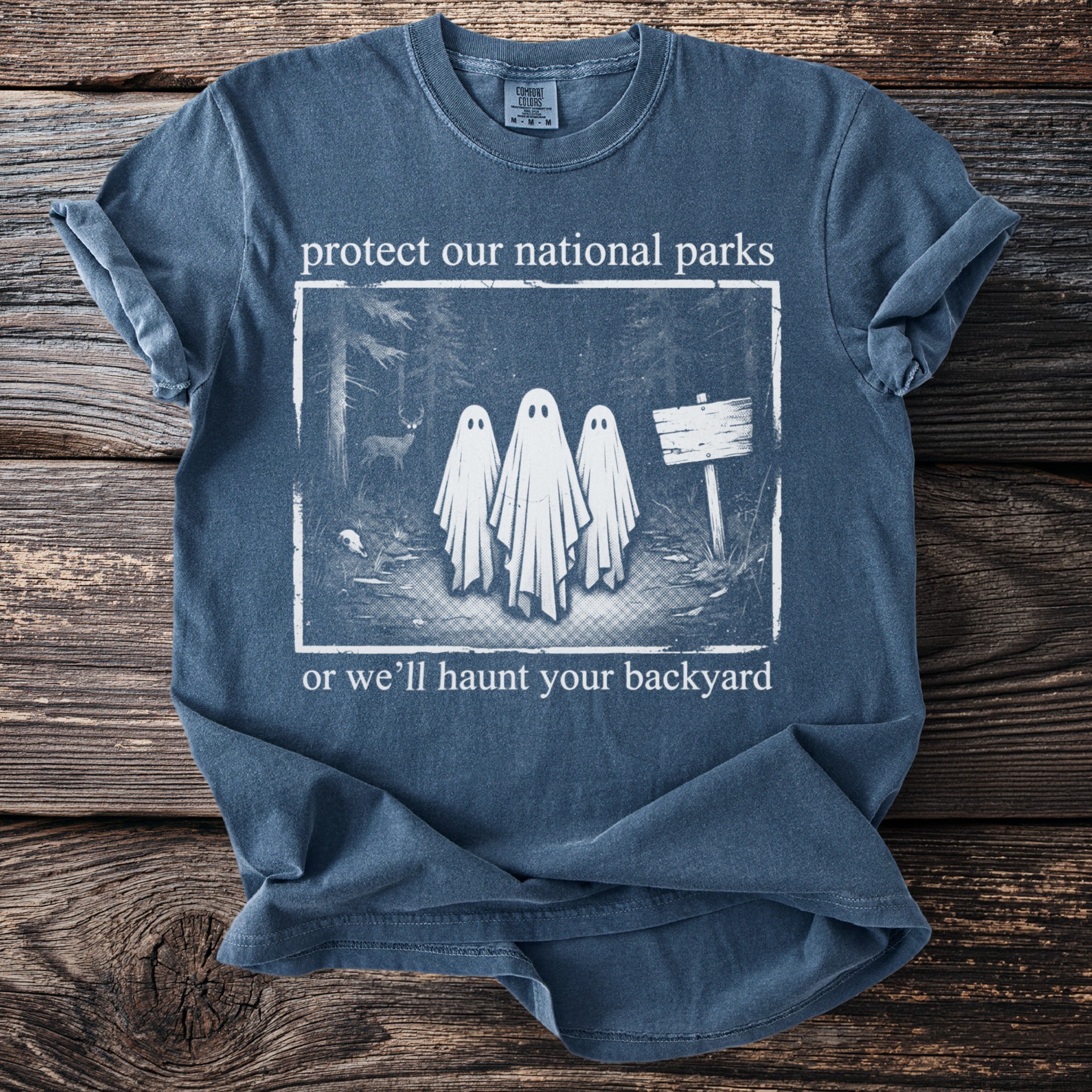 Blue t-shirt with "protect our national parks or we'll haunt your backyard" and ghost graphic.