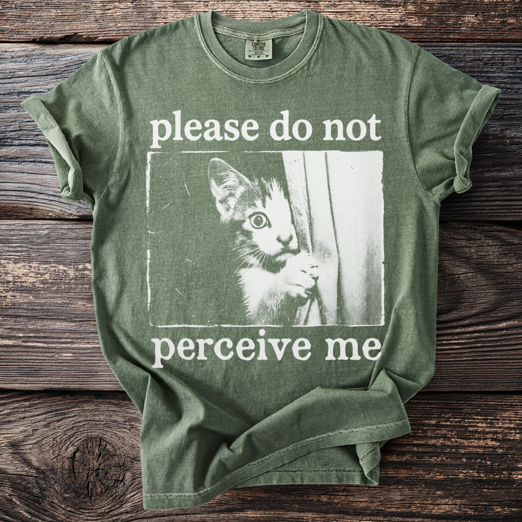 Green t-shirt with white text "please do not perceive me" and cat graphic.