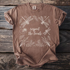 Brown t-shirt with white dragonfly and floral design; text says "respect the locals".