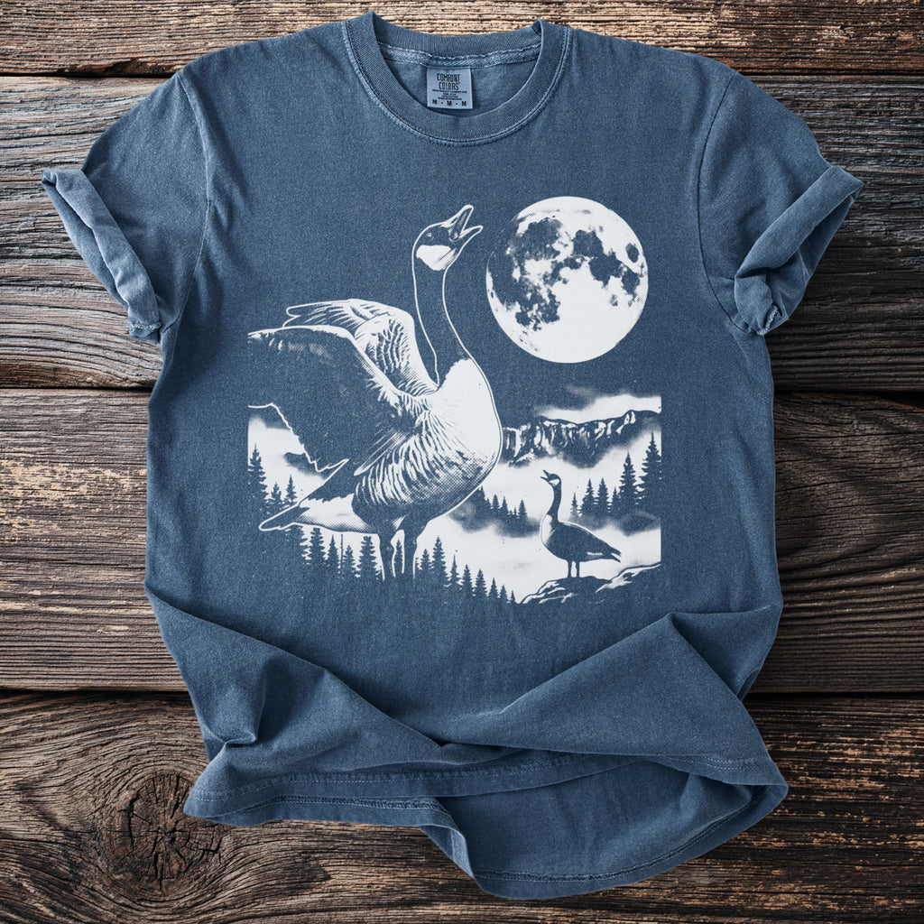 Blue t-shirt with graphic of geese in a forest under a full moon.