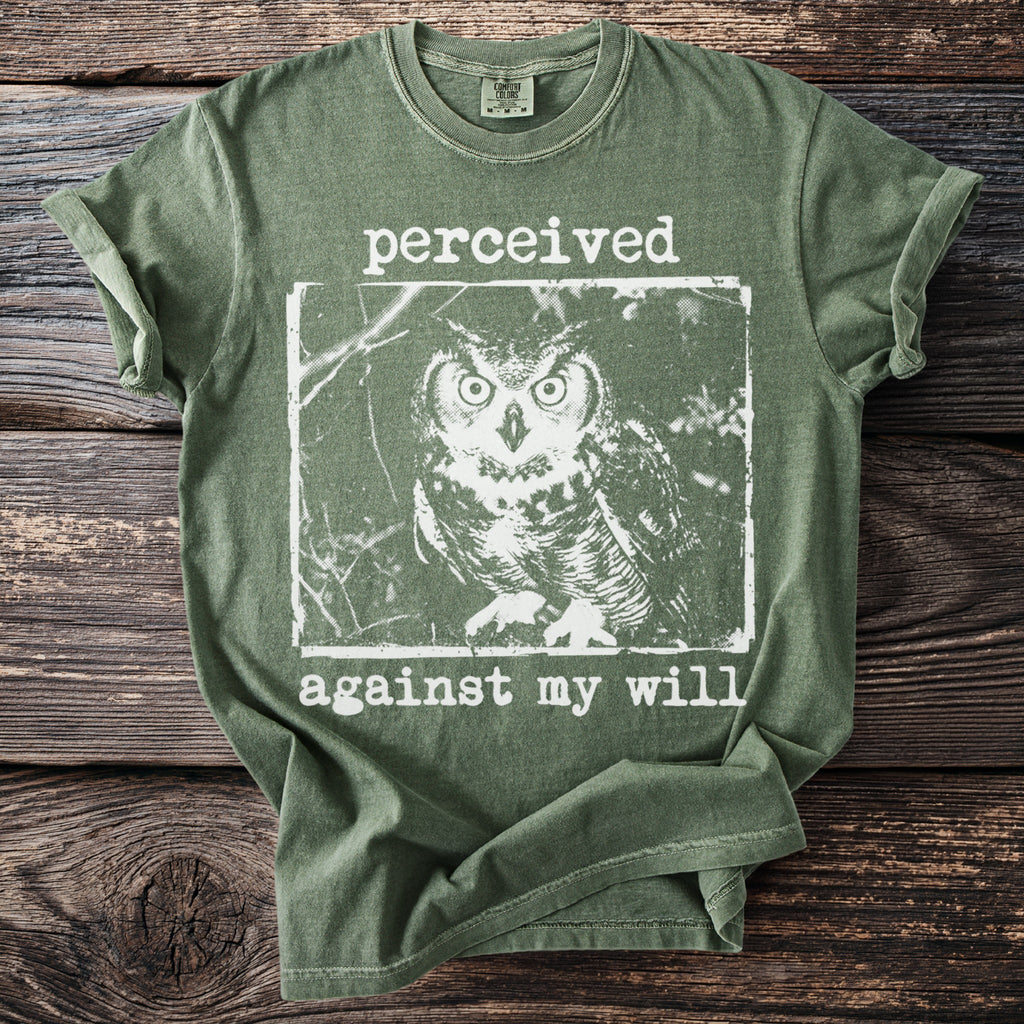 Green t-shirt with white graphic of an owl and text "perceived against my will".