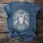 Blue t-shirt with a cream ram skull, ravens, bones, moon, and runes graphic.
