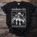 Black t-shirt with "sunken city dead but dreaming" and creature graphic.