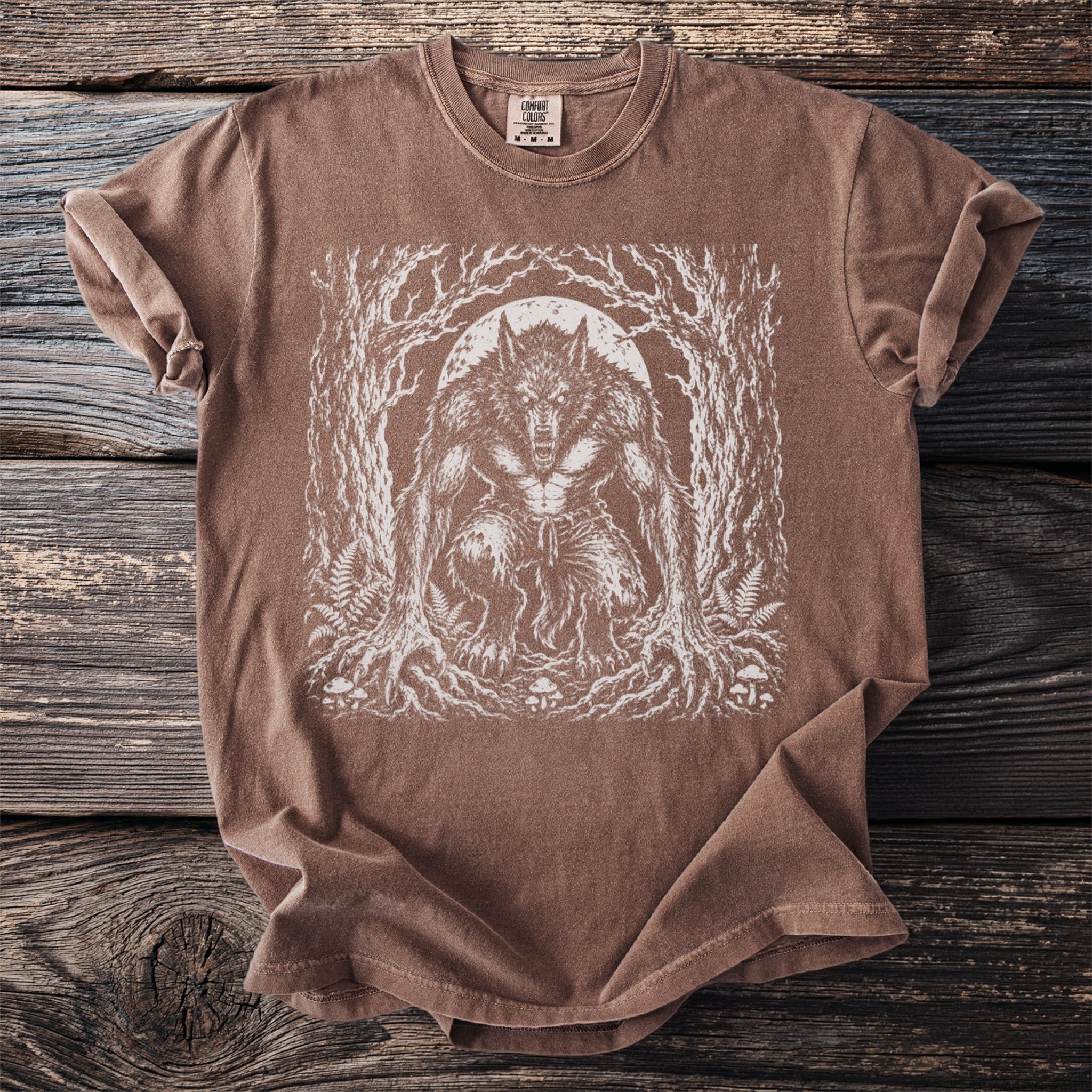 Brown Comfort Colors t-shirt with white werewolf forest moon graphic.