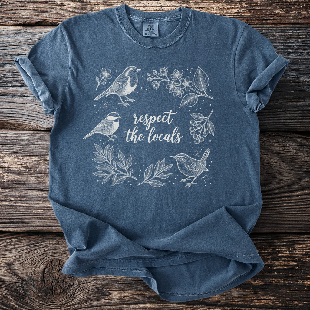 Blue t-shirt with white line art of birds, branches, and the text "respect the locals".