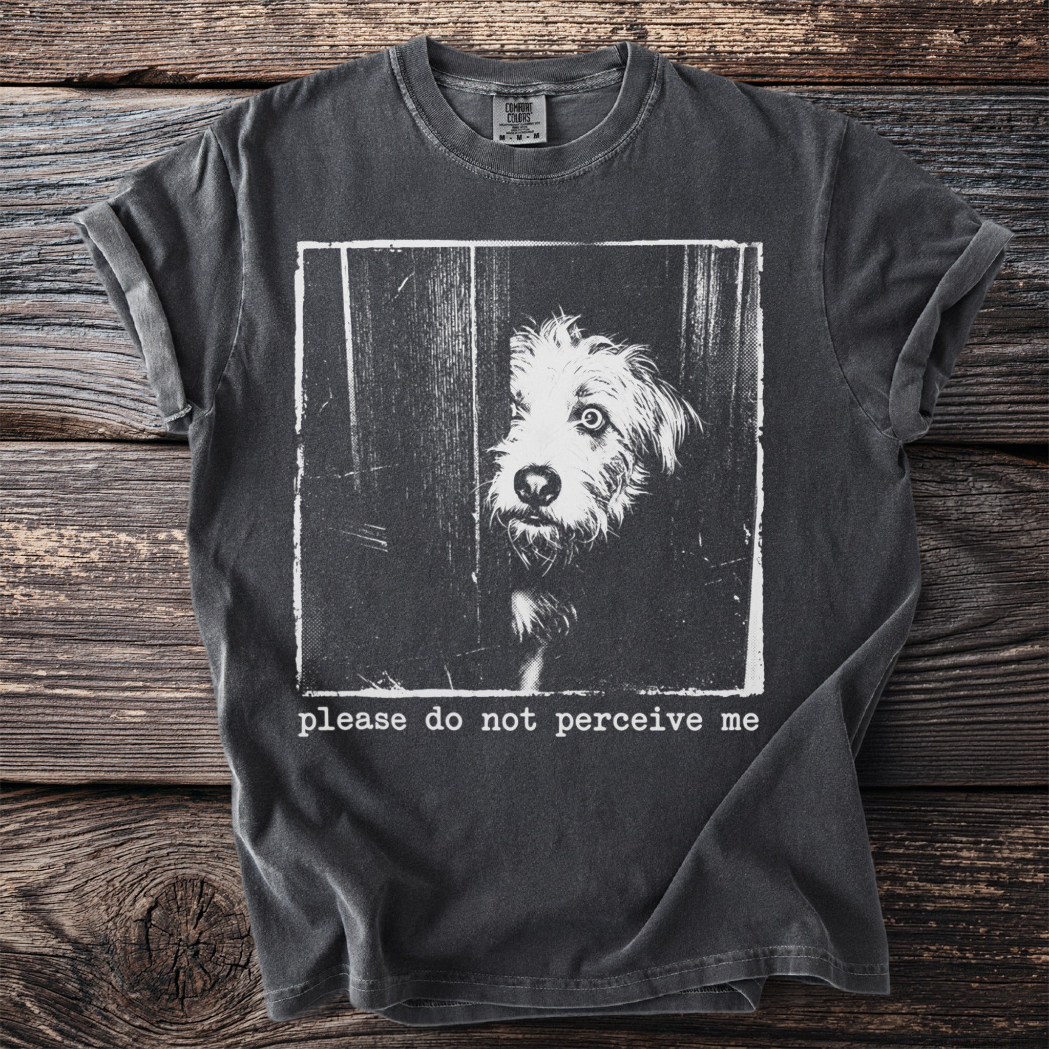 Dark grey t-shirt with white graphic of a dog's face peering through slats and text "please do not perceive me".