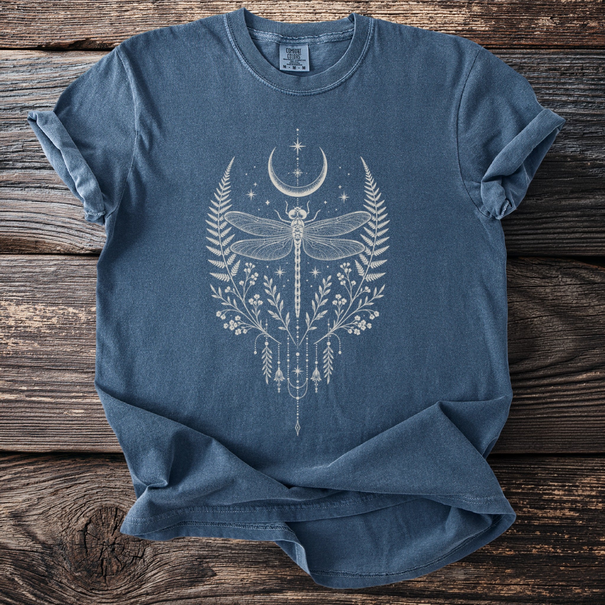 Blue t-shirt with a white dragonfly, crescent moon, and floral graphic.