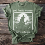 Green t-shirt with graphic and text "god forbid women have hobbies".