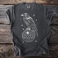 Dark gray t-shirt with white raven perched on a bone-patterned Christmas ornament.