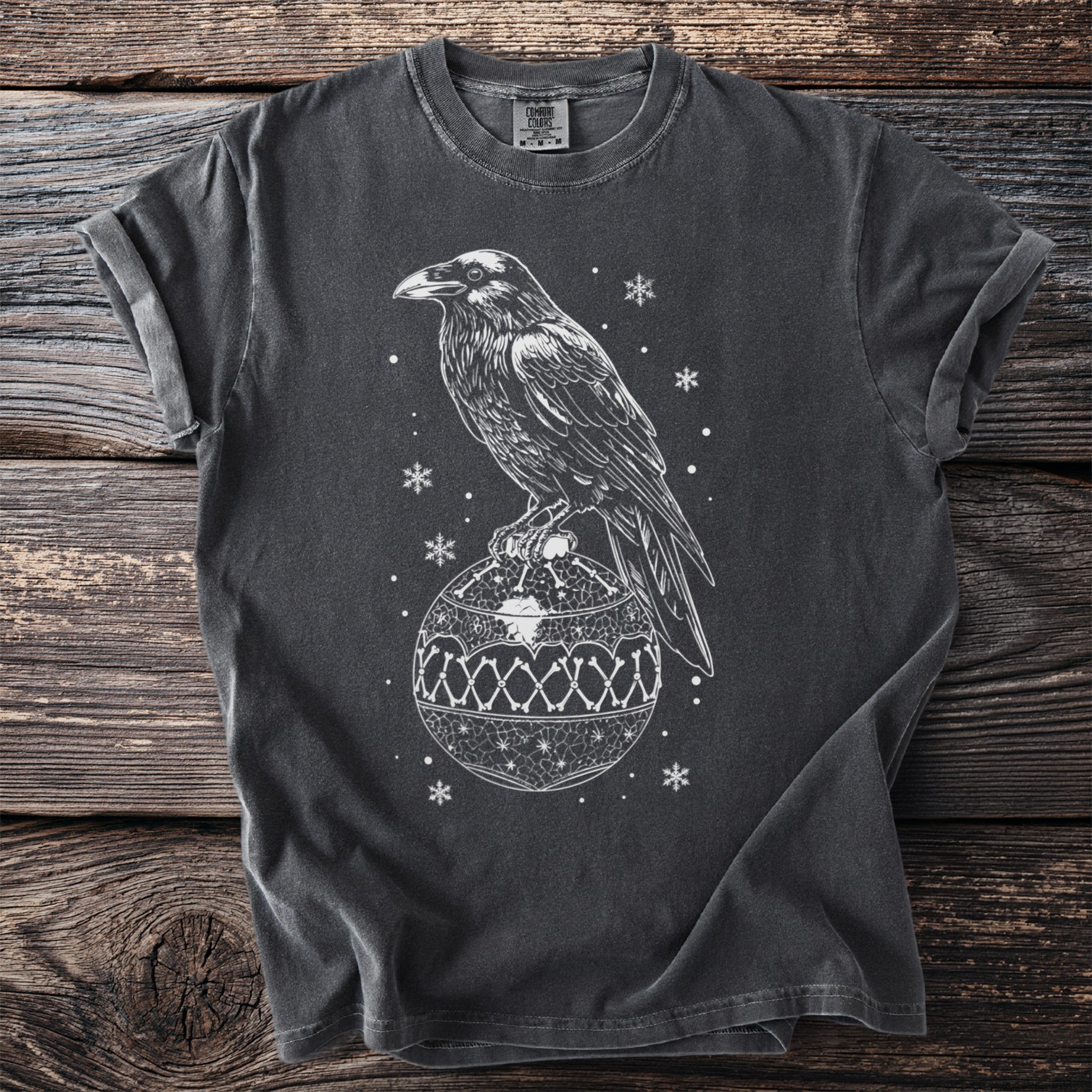 Dark gray t-shirt with white raven perched on a bone-patterned Christmas ornament.