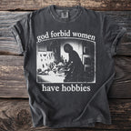 Dark grey t-shirt with graphic text "god forbid women have hobbies".