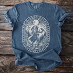Blue t-shirt with oval graphic of hiker, ravens, moon, and runes.