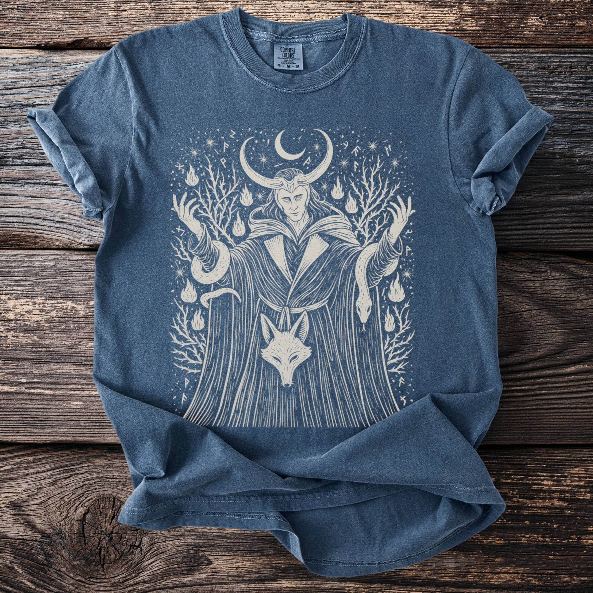 Blue t-shirt with a light tan graphic of Loki, a fox, and serpents.