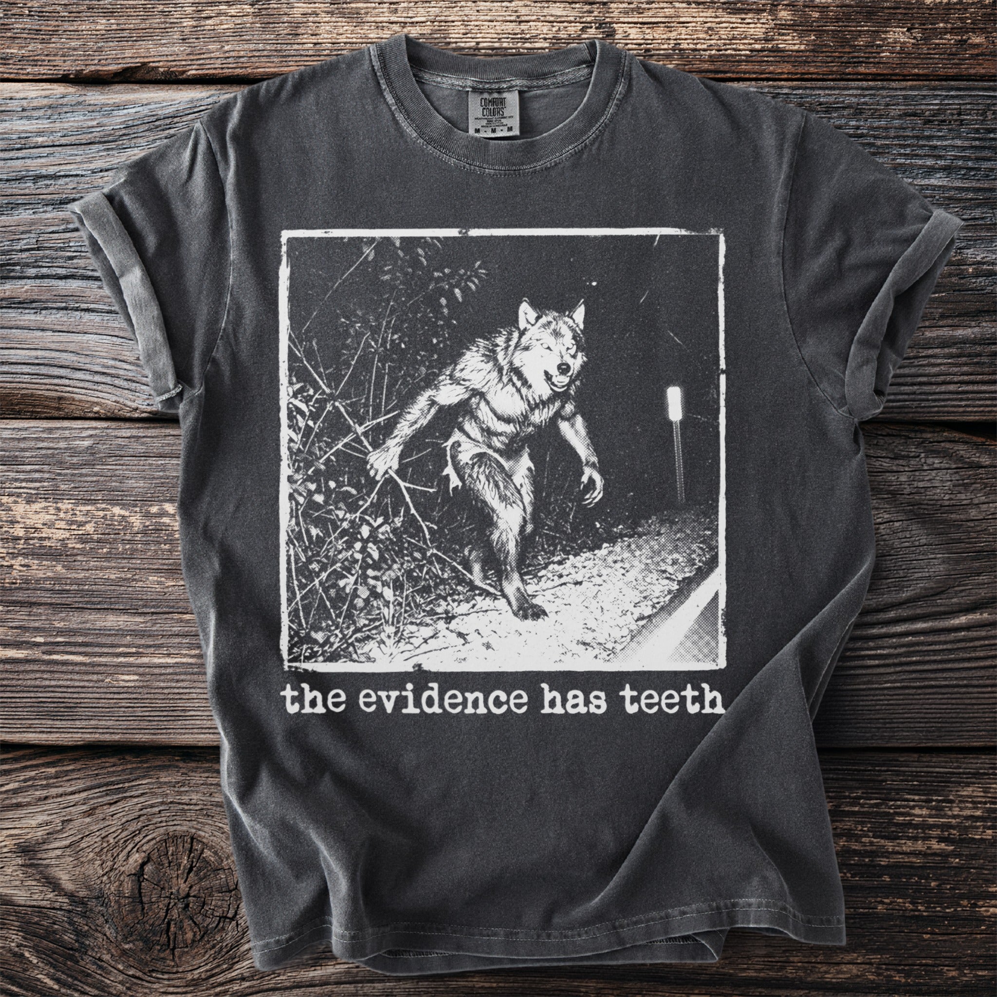 Dark t-shirt with graphic of a werewolf and text "the evidence has teeth."