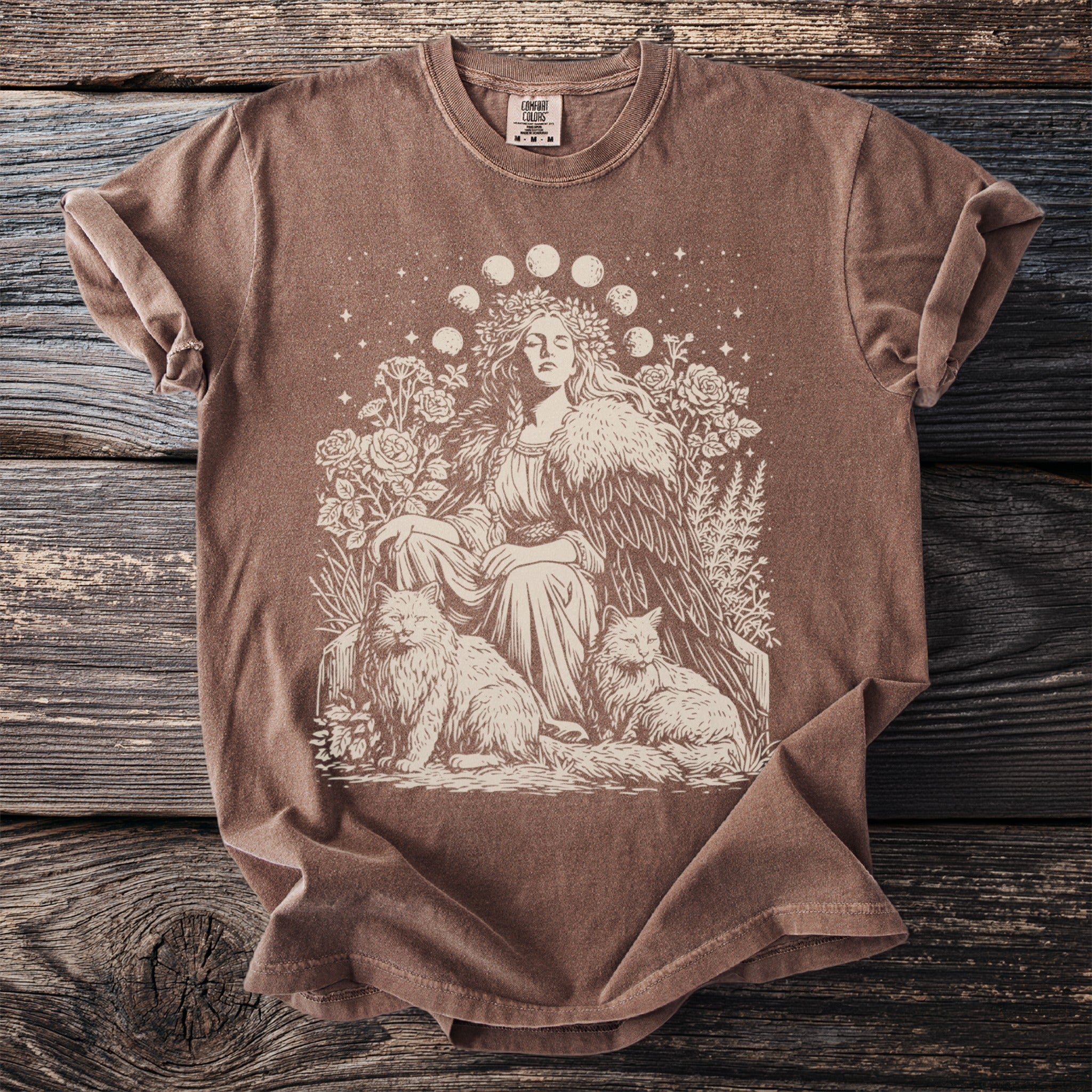 Brown t-shirt with cream graphic of a woman, two cats, and moon phases.