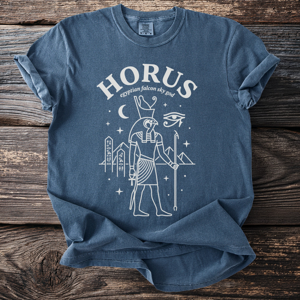 Blue t-shirt with white line art of Egyptian god Horus and stars.