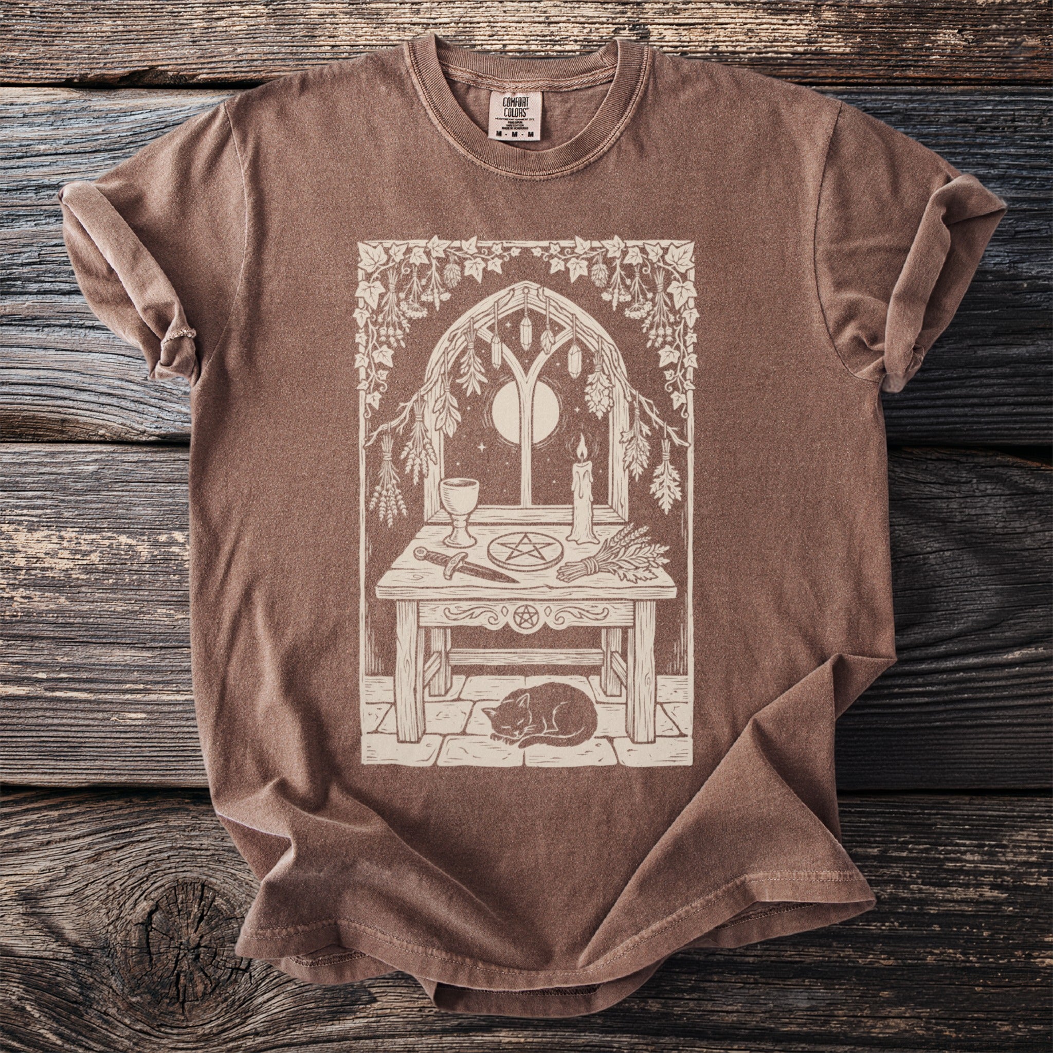 T-shirt with a light brown comfort colors tag and a mystical scene graphic.