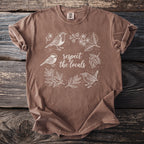 Brown t-shirt with white line art of birds and plants, reading "respect the locals".