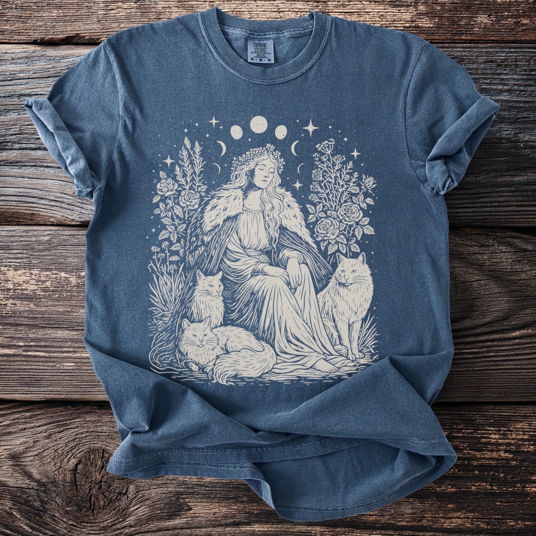 Blue t-shirt with cream linocut print of woman with cats and celestial moons.
