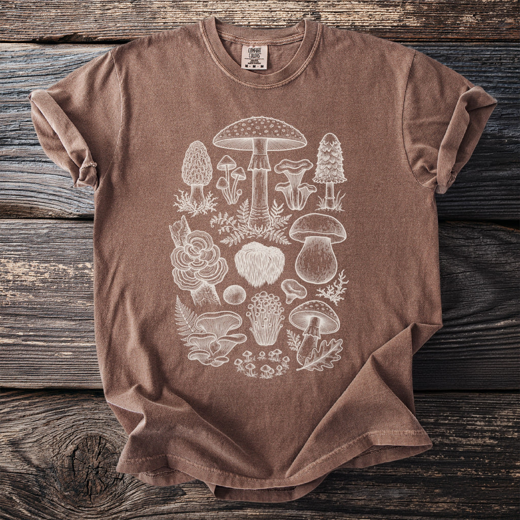 Brown t-shirt with a white line drawing of various mushrooms and ferns.