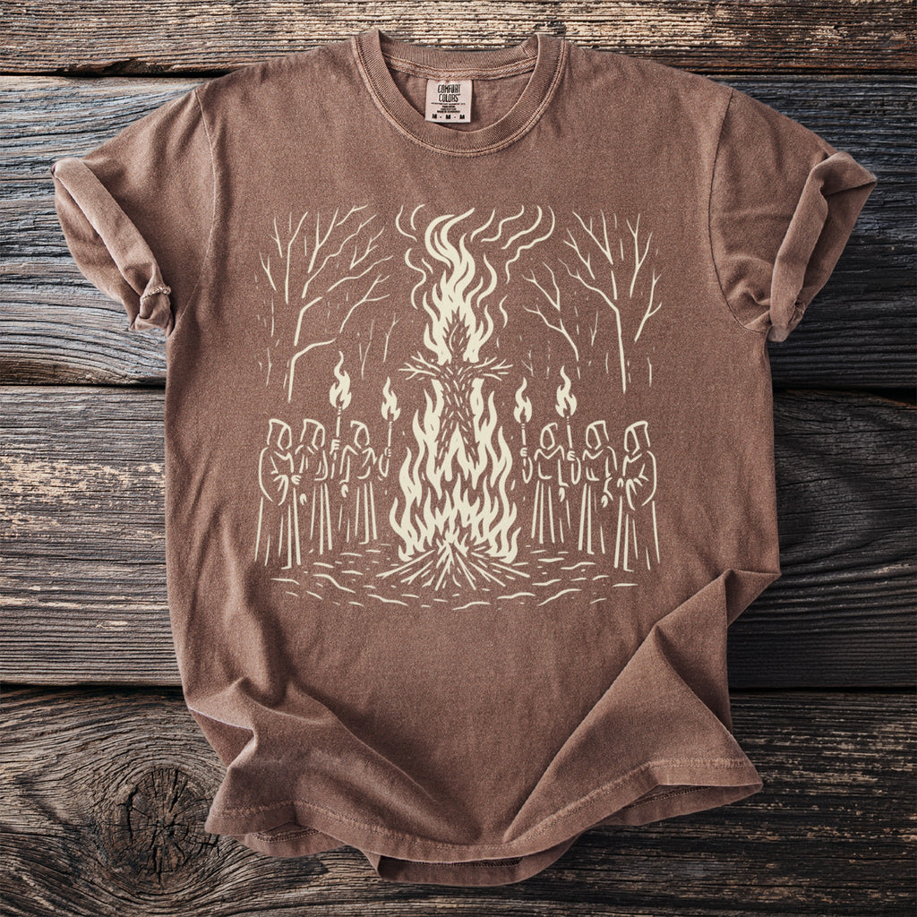 Brown t-shirt with a cream graphic of a bonfire with figures holding torches.