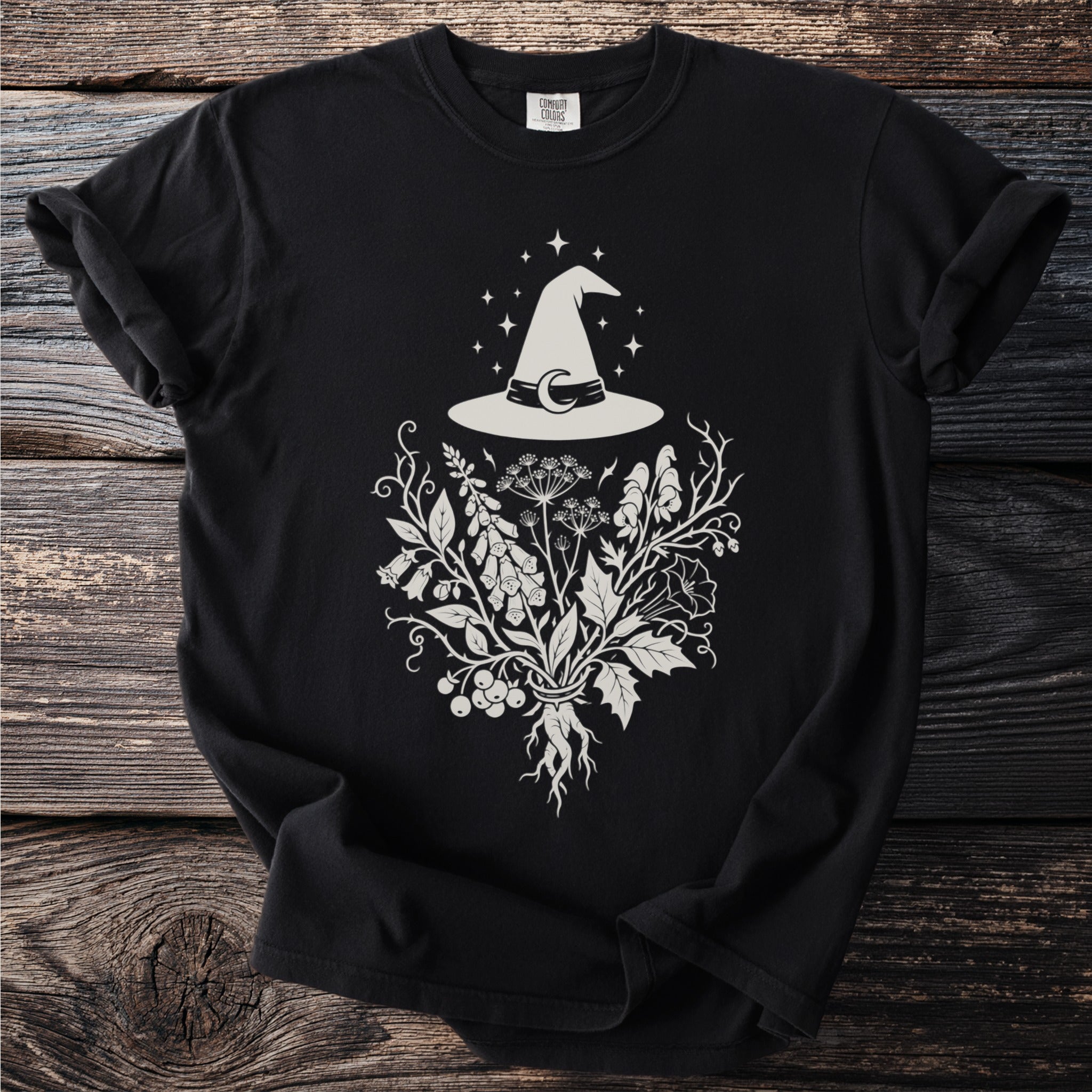 Black t-shirt with a white witch hat, moon, stars, and botanical illustration.