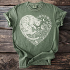 Green t-shirt with a white heart-shaped design of two cats surrounded by flowers and a moon.
