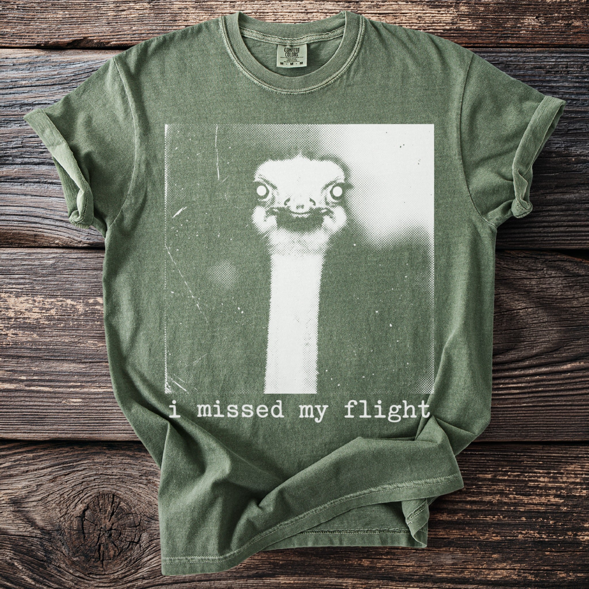 Green t-shirt with an ostrich face graphic and text "i missed my flight".