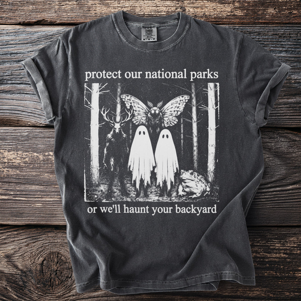 Dark t-shirt with surreal forest design "protect our national parks or we'll haunt your backyard"
