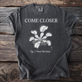 Dark t-shirt with "COME CLOSER" and a Venus flytrap illustration, labeled "Fig. 1: Poor Decision."