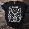 Black t-shirt with a white linocut maneki-neko cat holding a coin marked with stylised characters, among flowers.