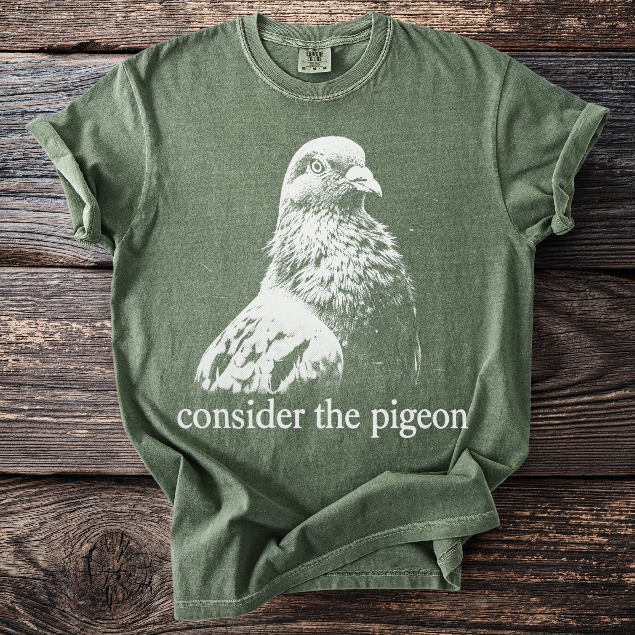 Olive Comfort Colors t-shirt with white pigeon graphic and "consider the pigeon" text.