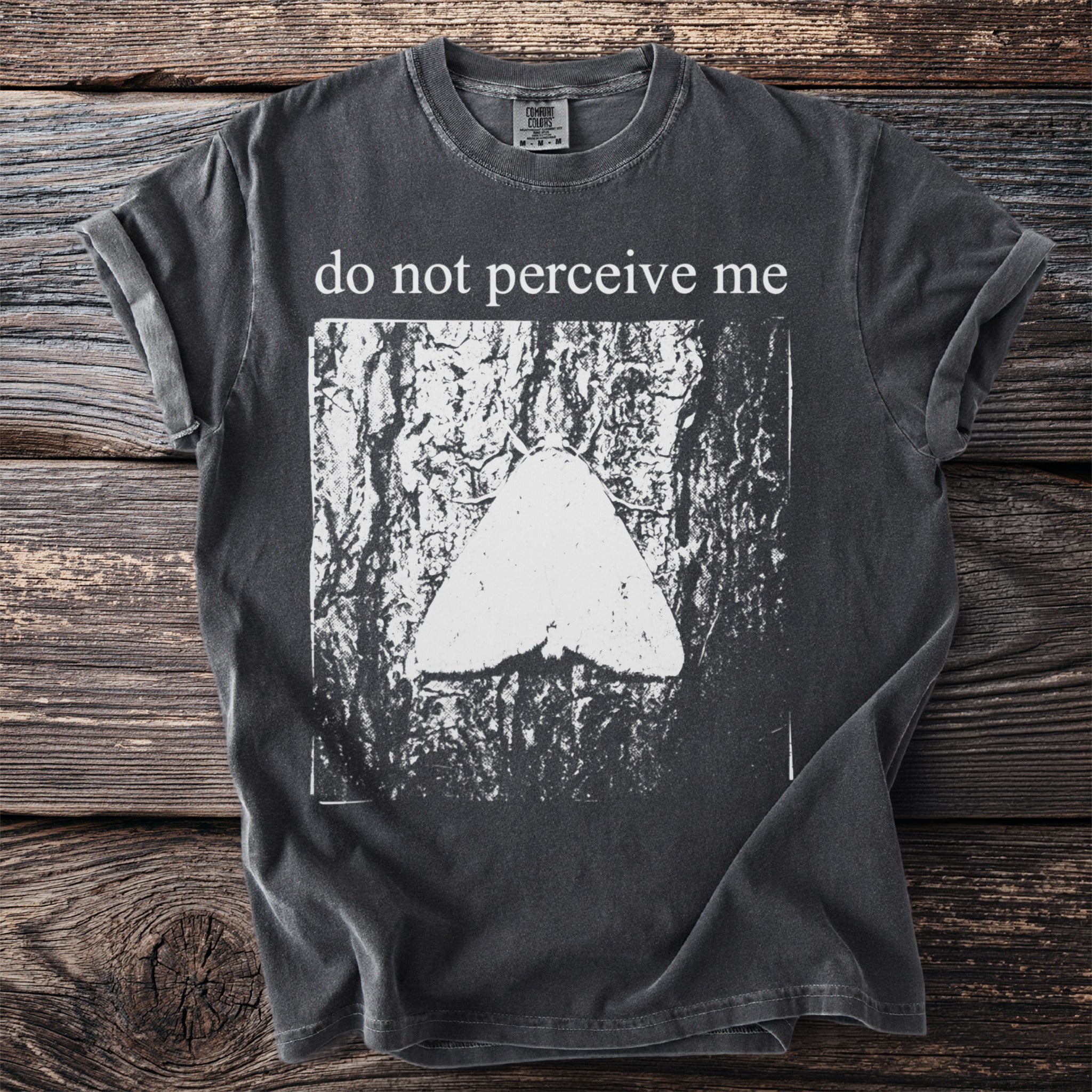 Dark grey t-shirt with white "do not perceive me" text and moth graphic.