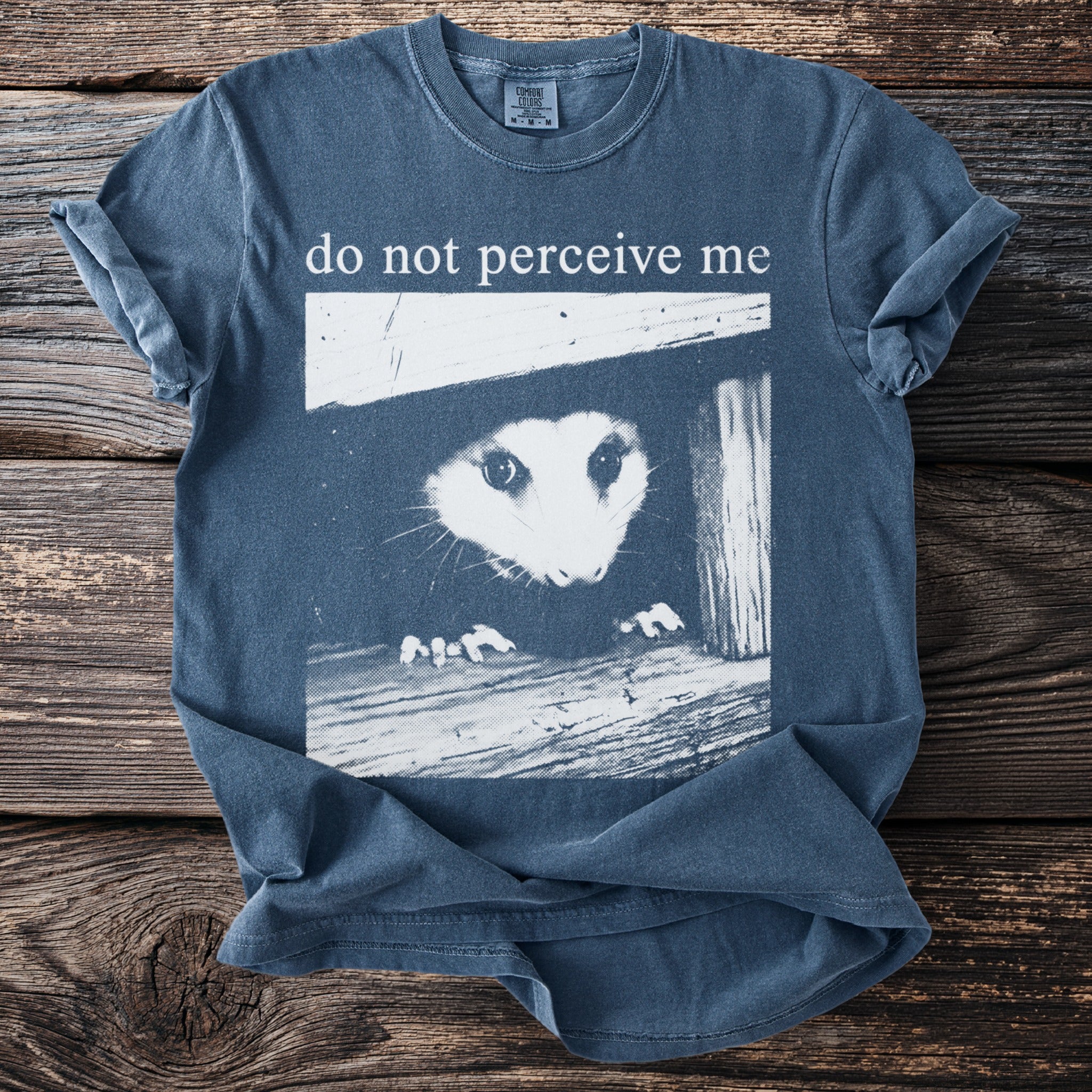 Blue t-shirt with opossum graphic and text "do not perceive me"