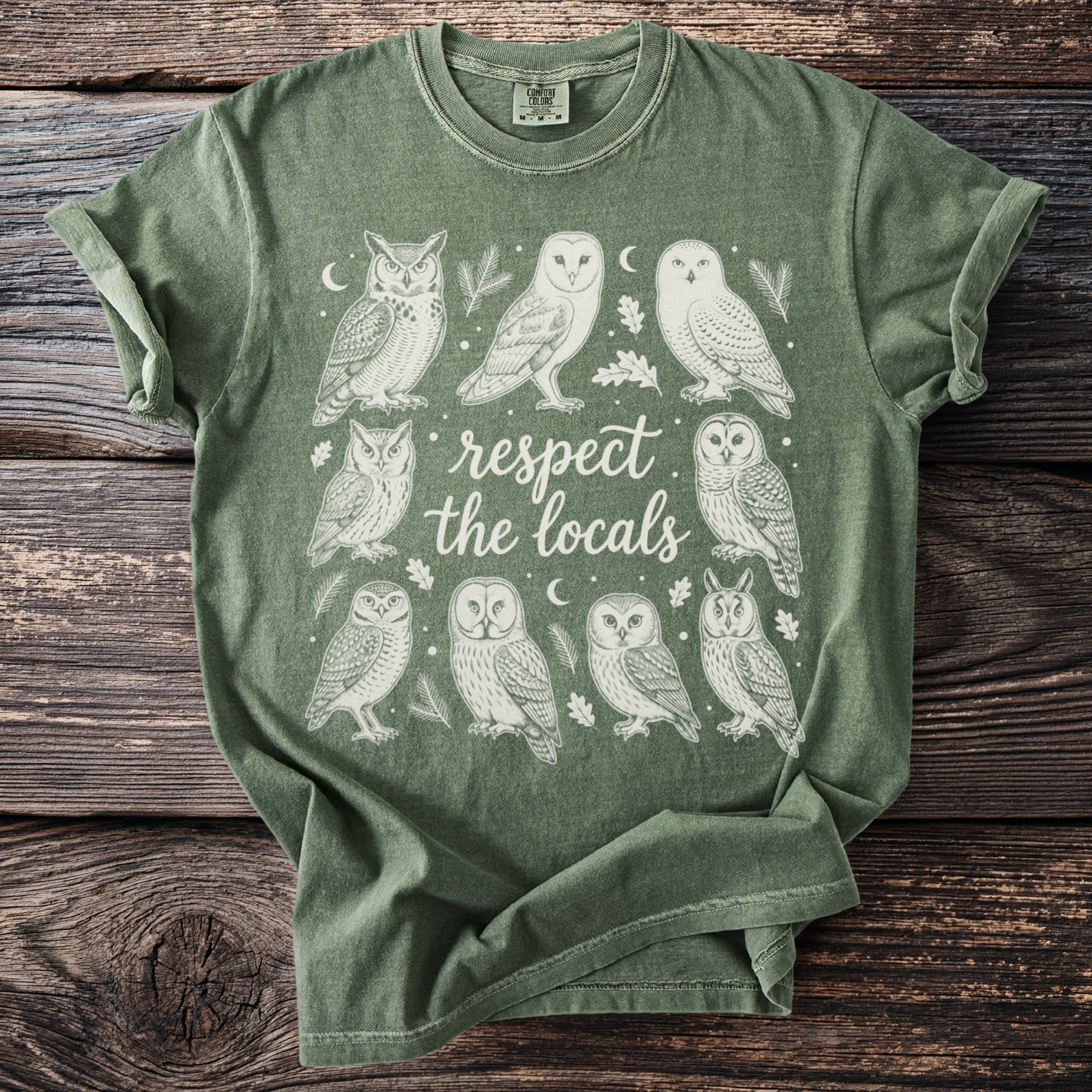 Green t-shirt with a circular owl graphic and "respect the locals" text.