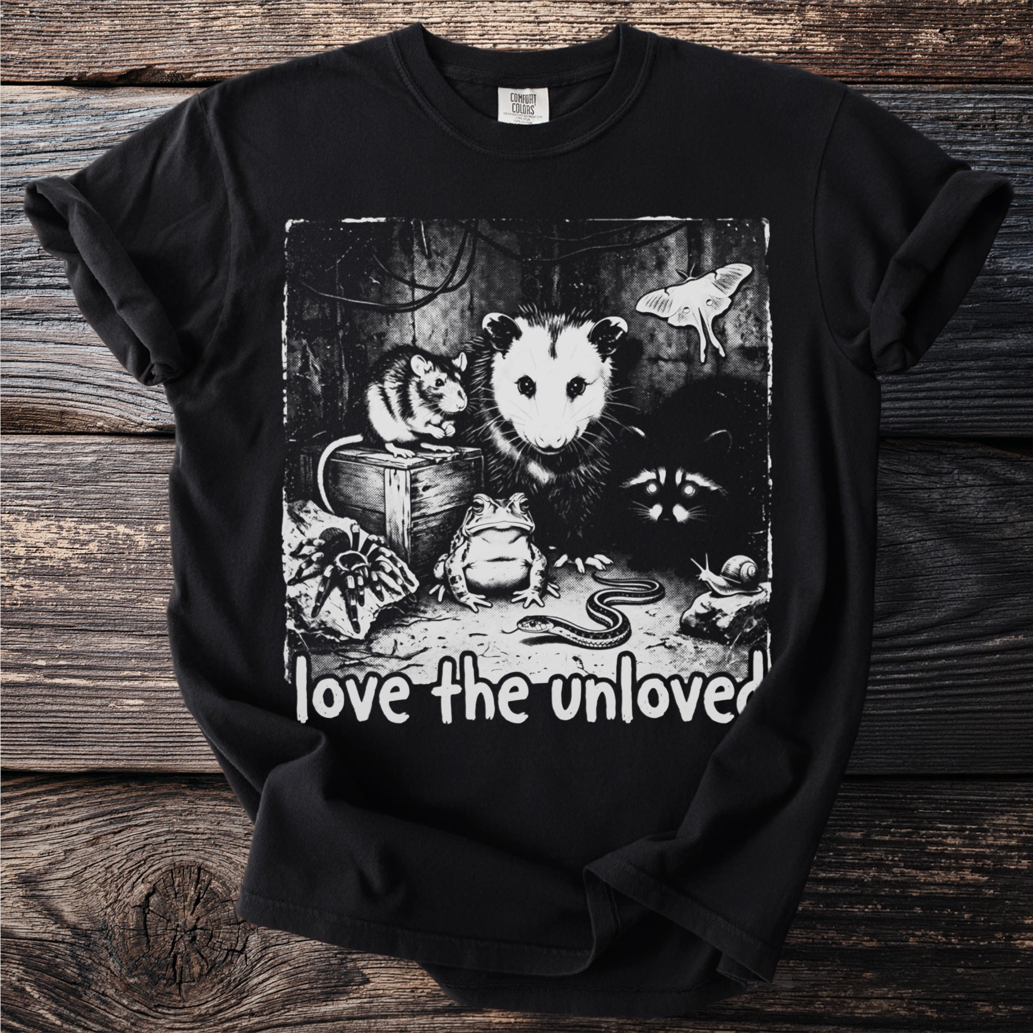 Black t-shirt with a graphic of an opossum, mouse, raccoon, frog, snake, spider, snail, and moth with text "love the unloved".