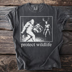 T-shirt with Bigfoot, mothman, and deer skull graphic and "protect wildlife" text.